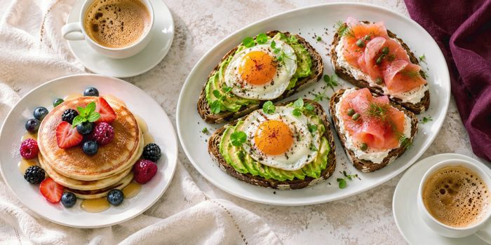 Mesa de brunch con pancakes, tostadas con huevo y salmón